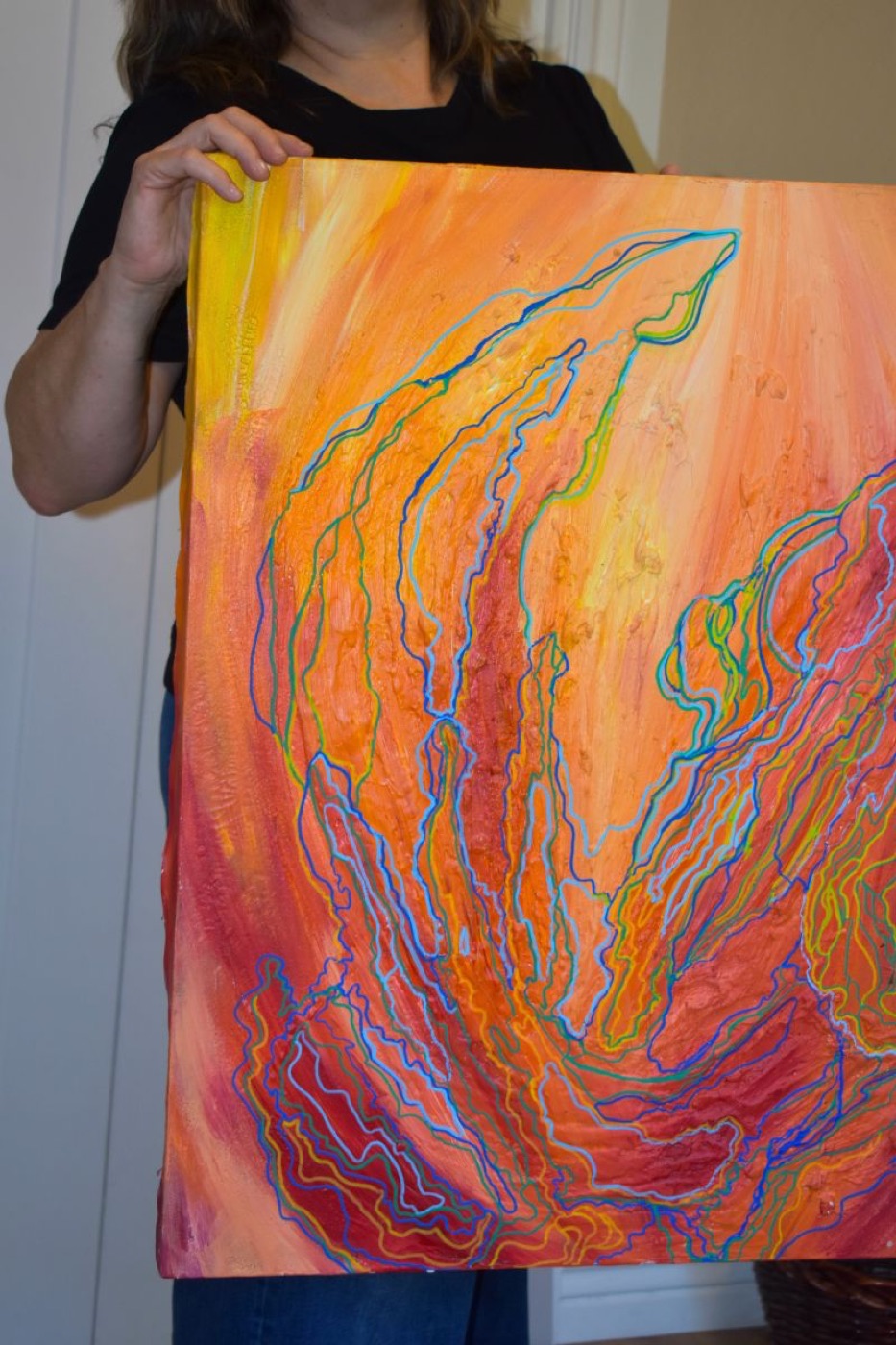 Diane holding a large orange acrylic canvas in progress